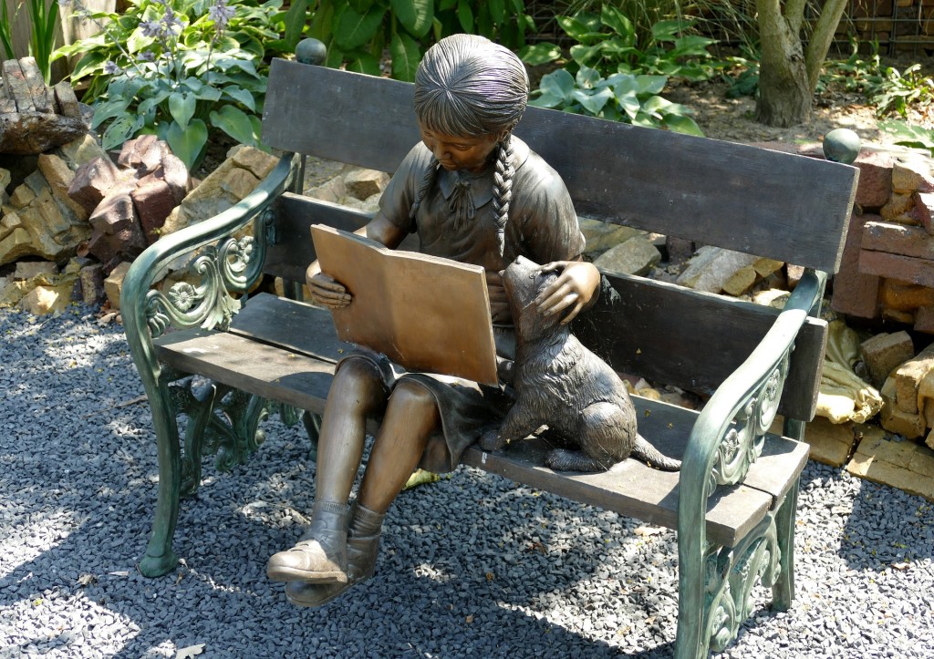 dog helps child read statue